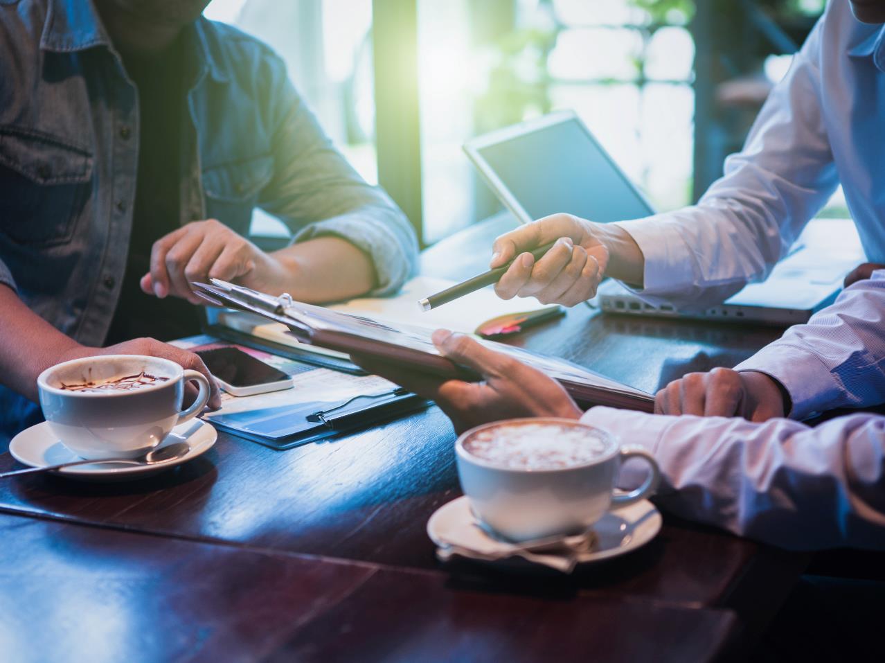 mennesker der sidder ved et bord med kaffe og diskuterer