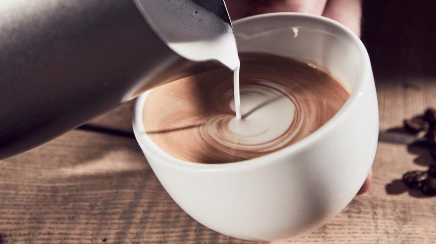 Kontorbord med computer og kaffekop