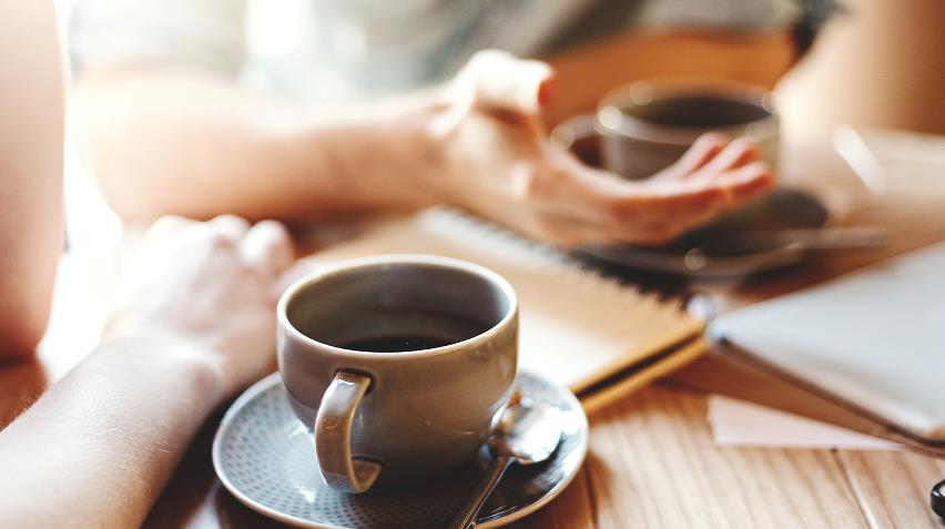 bord med mennesker omkring og kaffe på bordet